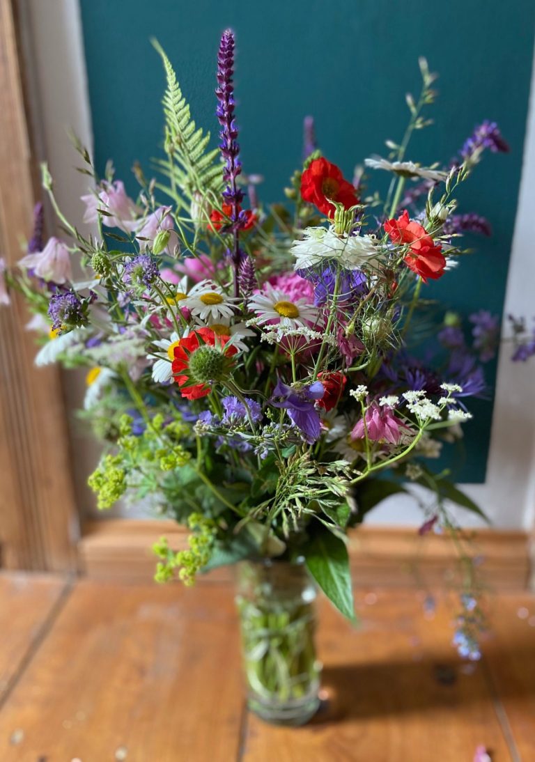 Bunte Frühlingsblumen in einer Vase, darunter Margeriten und Narzissen.